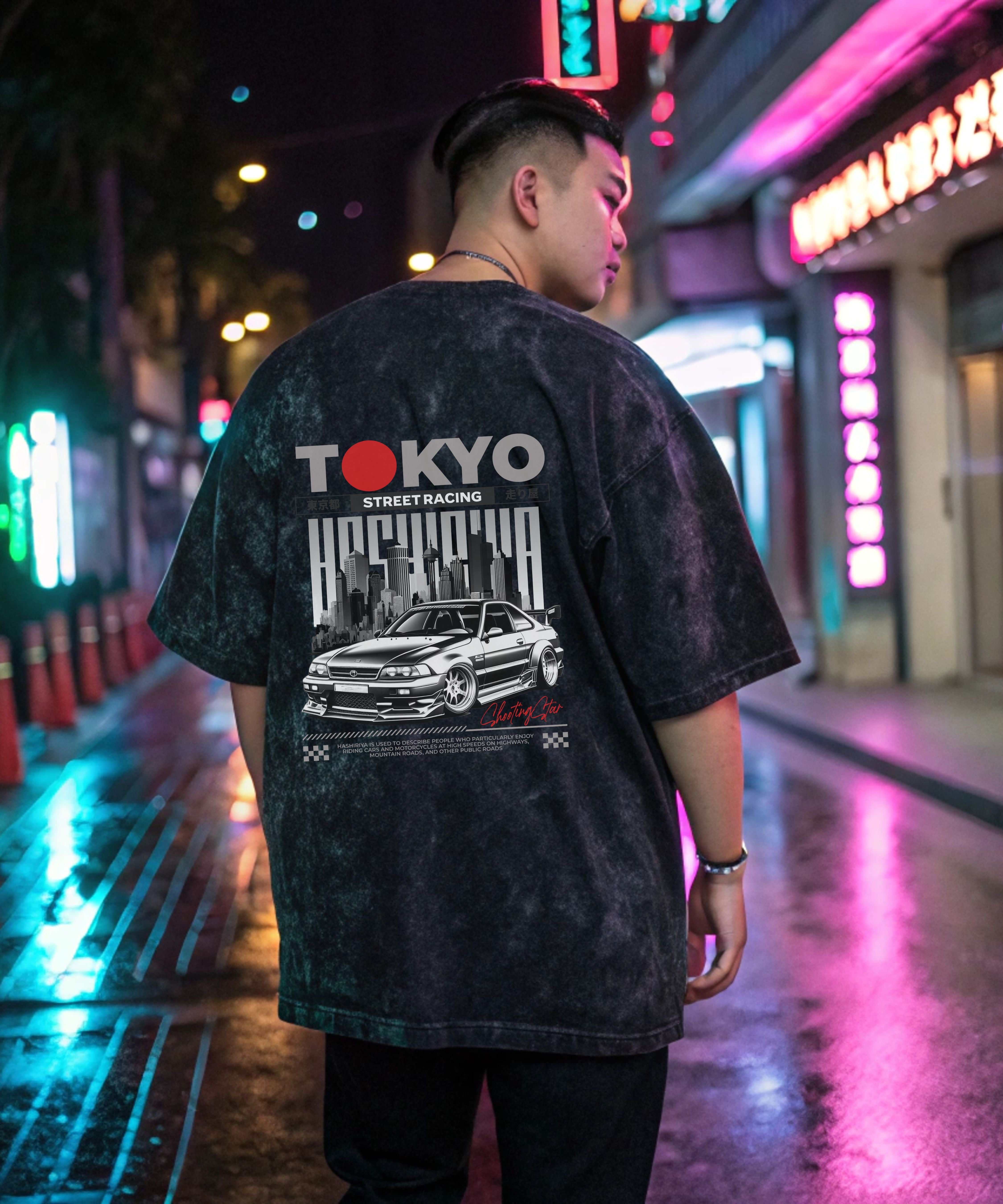Person wearing a black Acid Washed t-shirt with 'Tokyo' and car graphics on a neon-lit street.